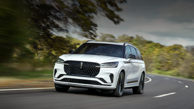 A white 2025 Lincoln Aviator® SUV is being driven down a road lined with trees. | Joe Cooper Lincoln of Edmond in Oklahoma City OK