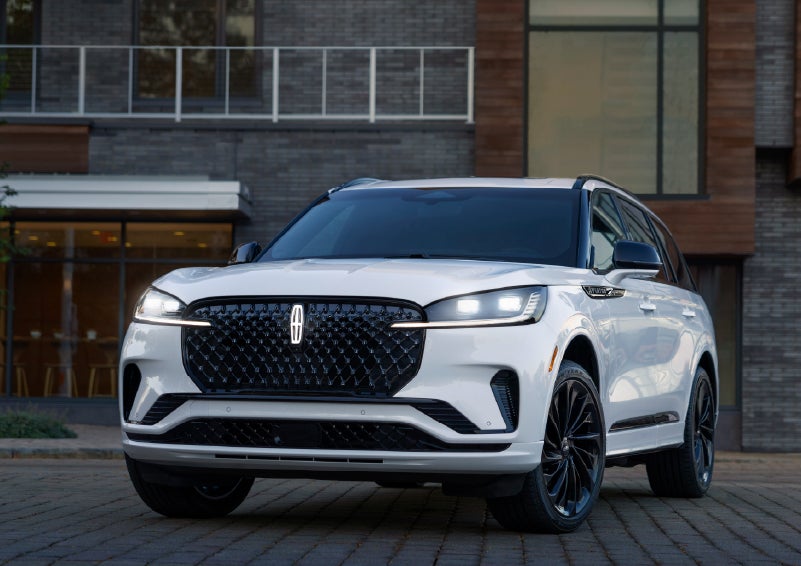A 2026 Lincoln Aviator® Reserve model is shown with the available Jet Appearance Package parked near a restaurant. | Joe Cooper Lincoln of Edmond in Oklahoma City OK