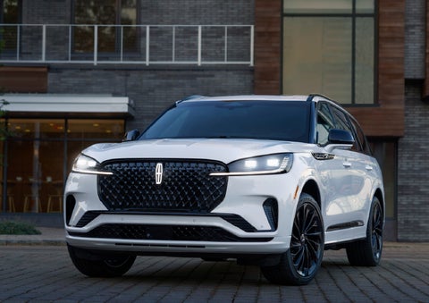 A 2026 Lincoln Aviator® Reserve model is shown with the available Jet Appearance Package parked near a restaurant. | Joe Cooper Lincoln of Edmond in Oklahoma City OK