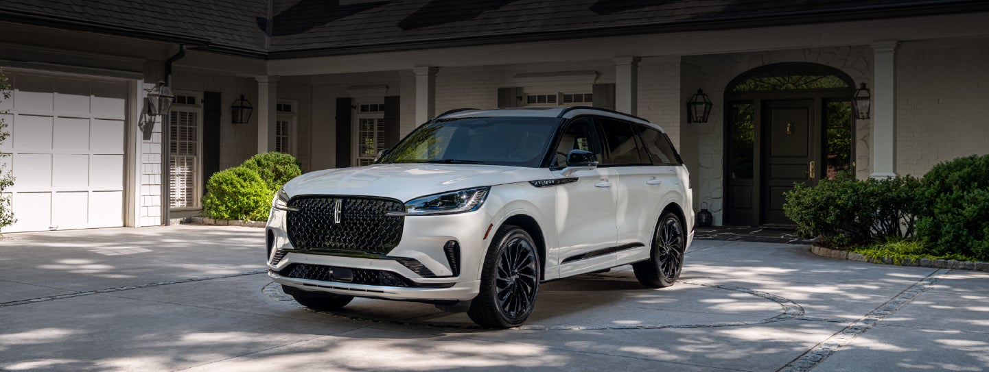 A white 2026 Lincoln Aviator® SUV is parked in the driveway of a luxury home. | Joe Cooper Lincoln of Edmond in Oklahoma City OK